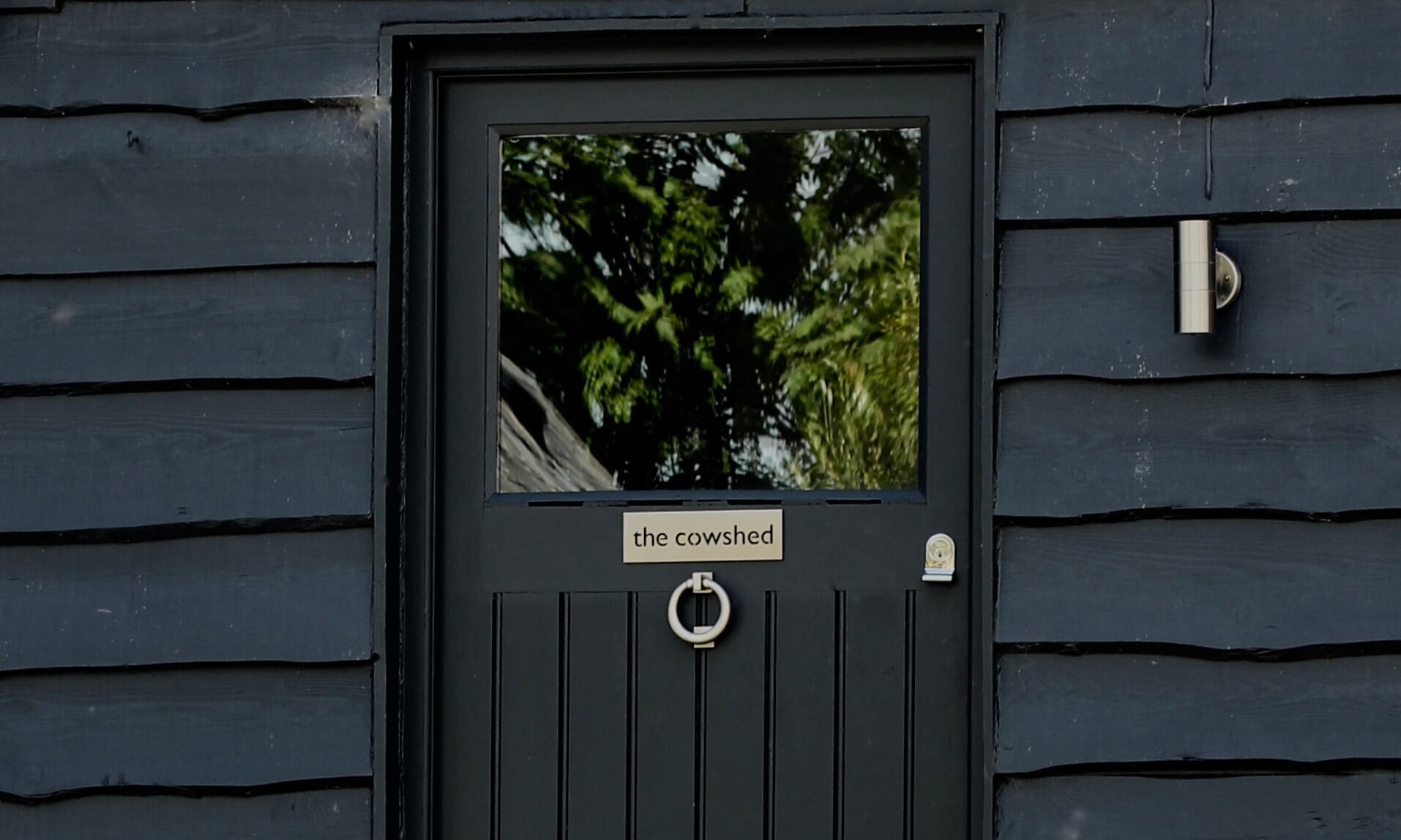 front door of a barn conversion painted in farrow & ball railings with cowshed sign