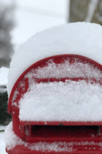 an English red post box in the cotswolds in a snowy landscape