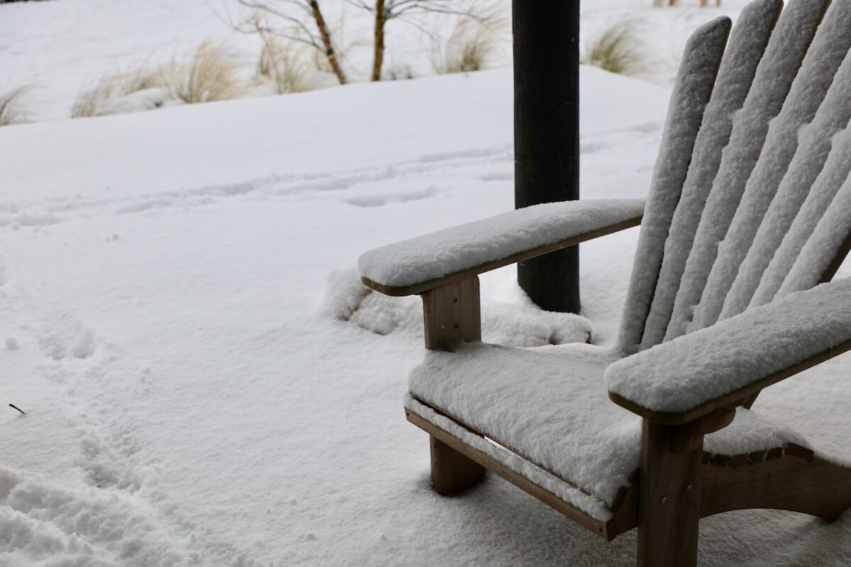 Adirondack chair covered in snow in a cotswolds landscape