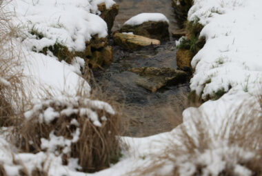 a stone rill breaks through snow in a cotswolds landscape design