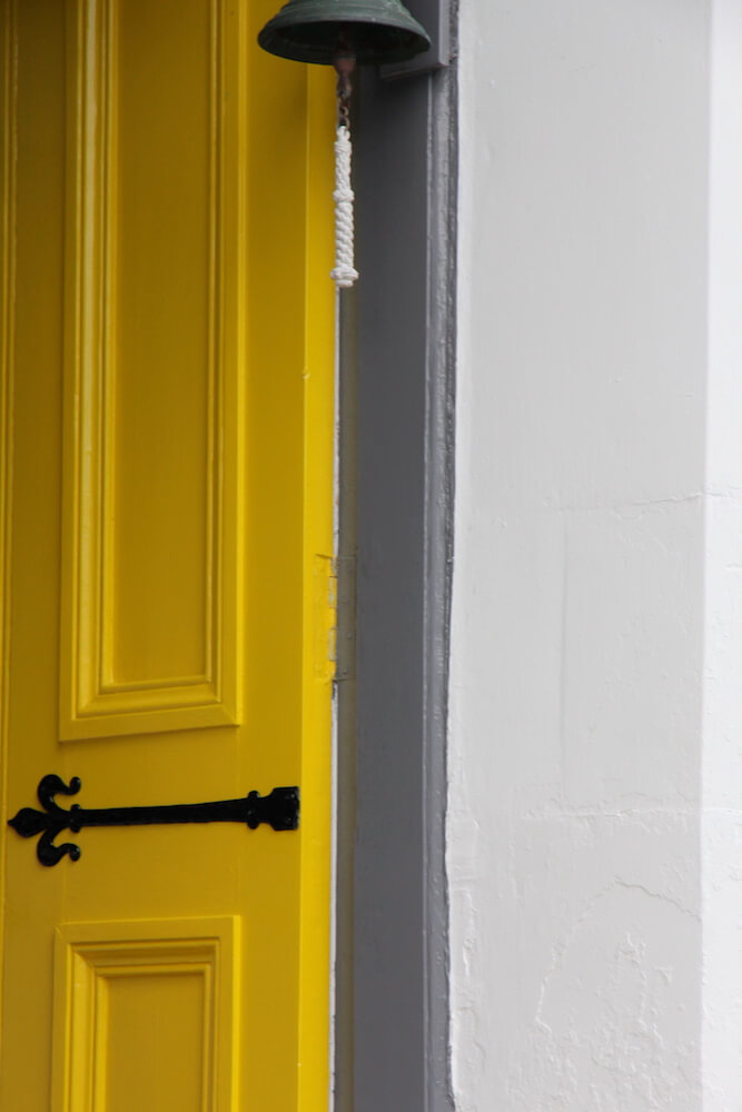 a yellow and grey door in farrow & ball paint opening to a cornwall garden design