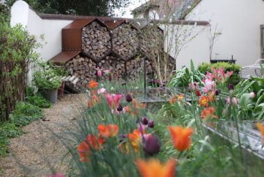 beehive shaped logstore wall with colourful tulips in a modern country style garden
