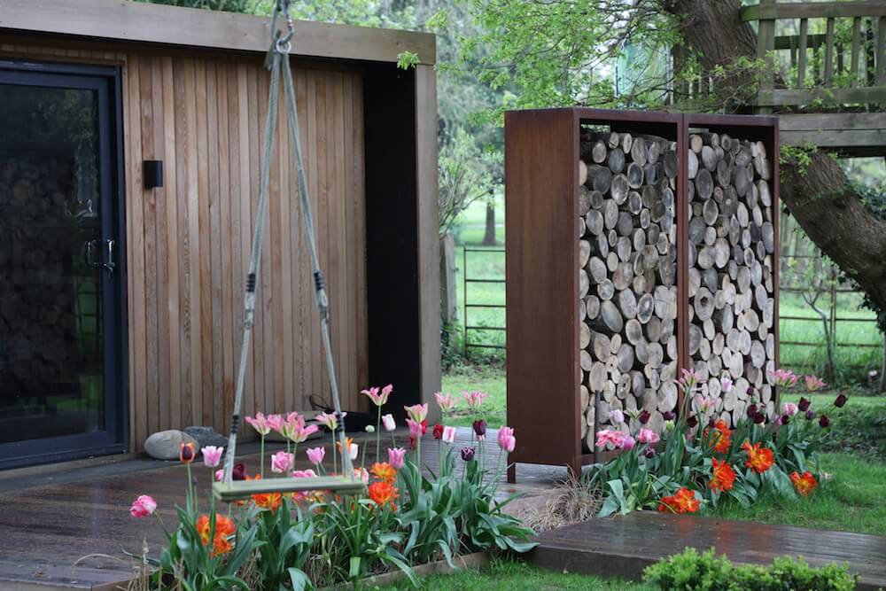 garden studio and log wall with swing in a modern country garden