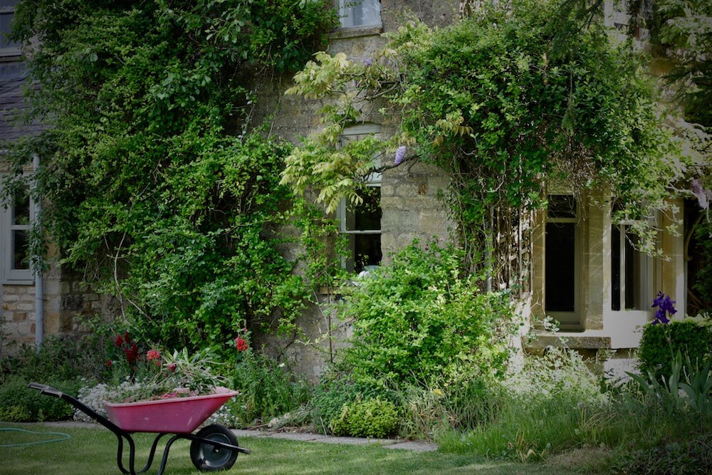 pink wheelbarrow in a Kingham garden victorian bay window