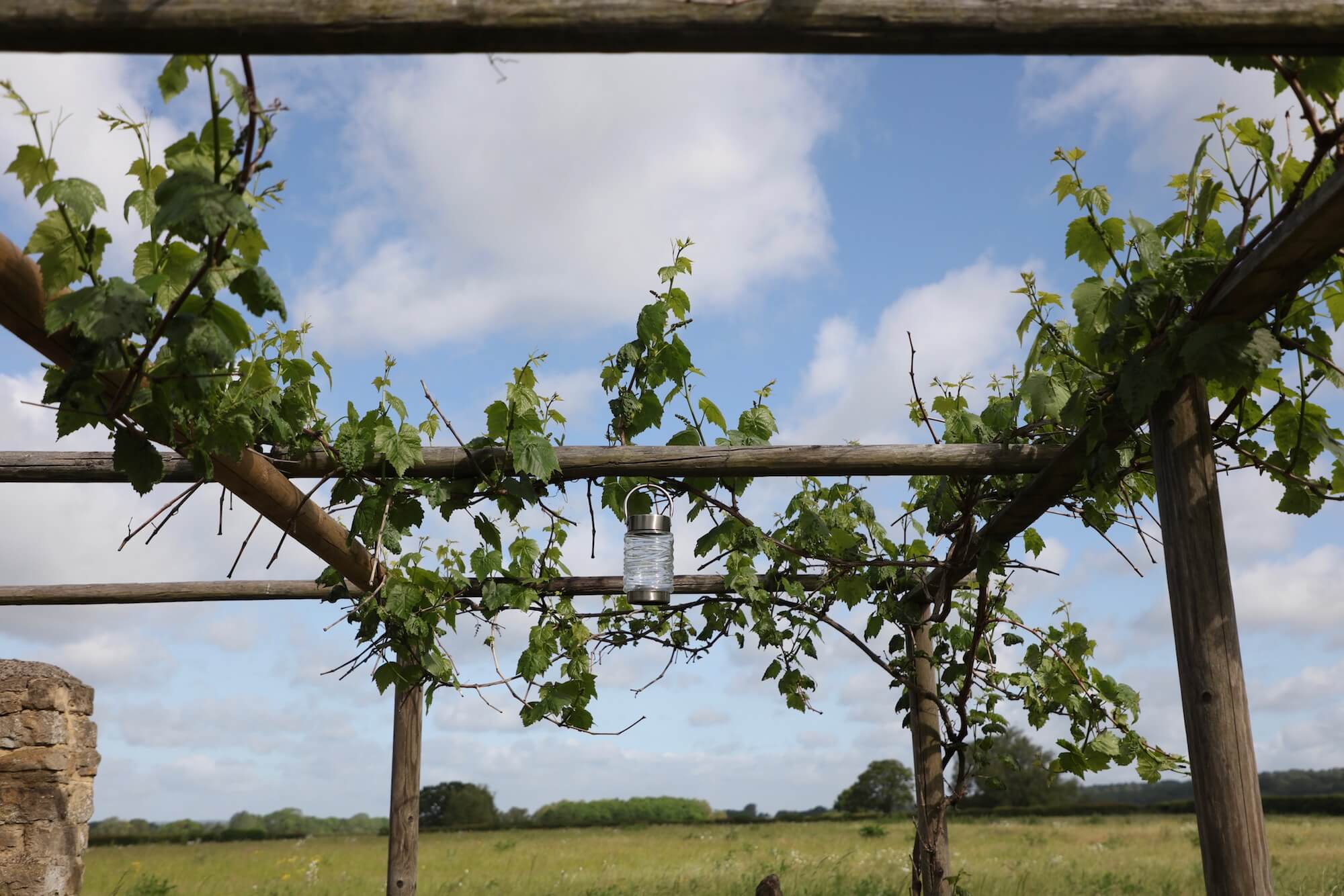 wooden garden pergola against blue sky and lanterns hanging from it