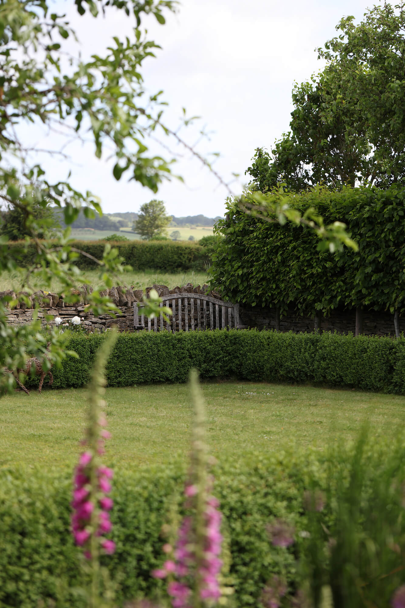 flowers against a green lawned Kingham village garden