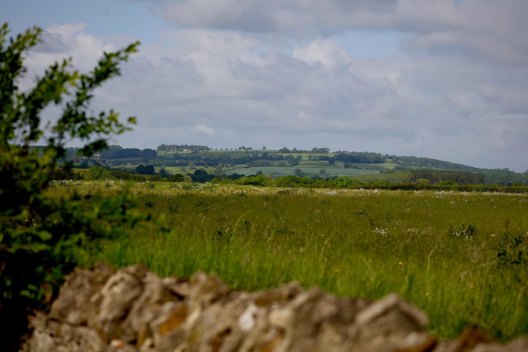 landscape view of Evenlode valley spring day hills sky and distant houses