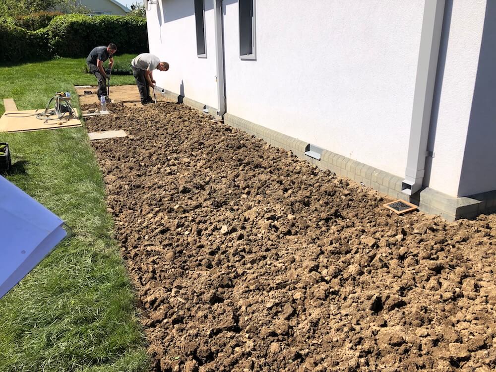 landscape men and women dressed in black planting a Padstow garden in front of a big house