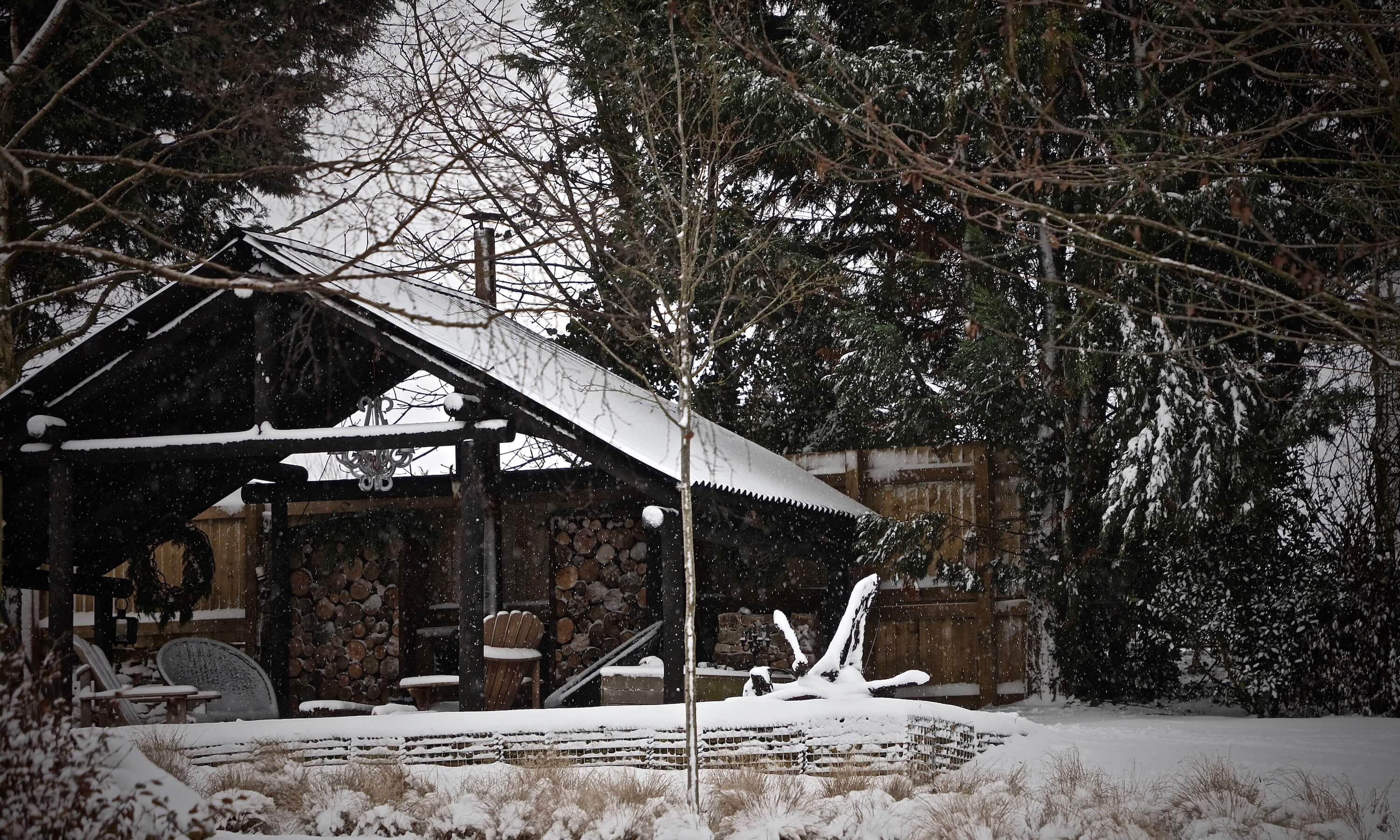 a black nordic garden shack with wood burners covered in snow in oxfordshire