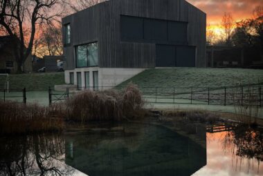 modern new build barn on a winter morning reflection in lake