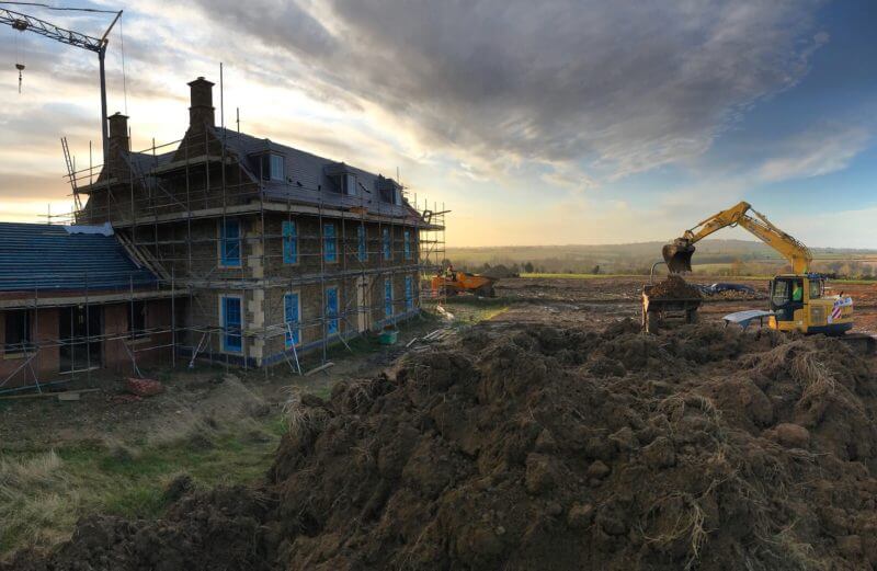 large Georgian farmhouse under construction with its grounds being landscaped