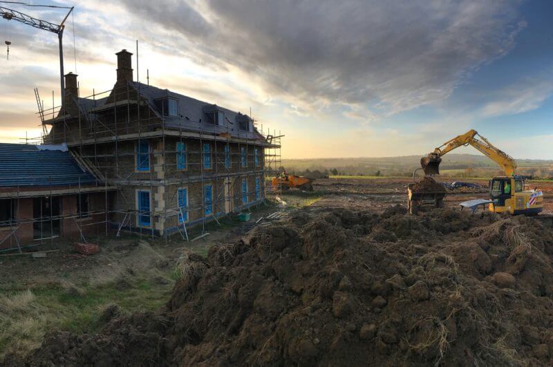 large Georgian farmhouse under construction with its grounds being landscaped