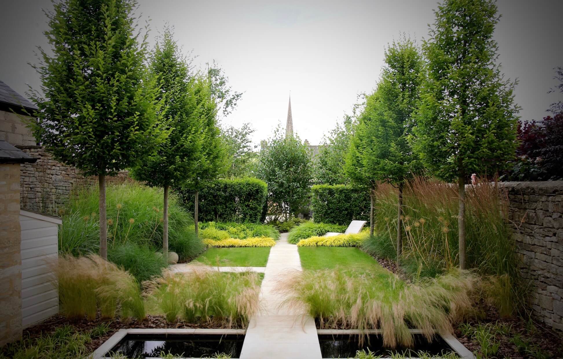 Burford garden with church steeple and arrow head tress