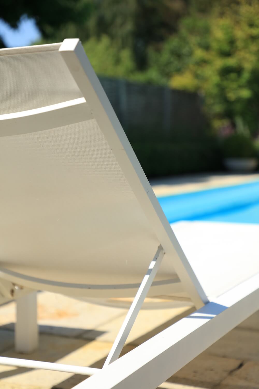 white sunlounger beside blue swimming pool