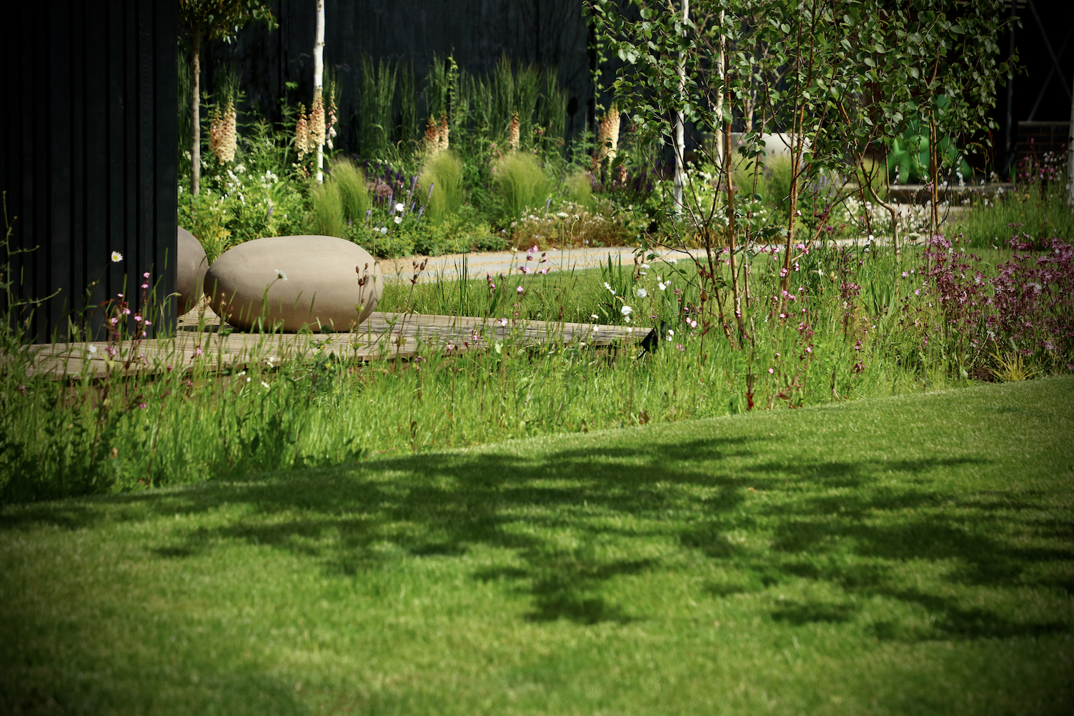 Giant clay pebble stools behind wildflower lawn