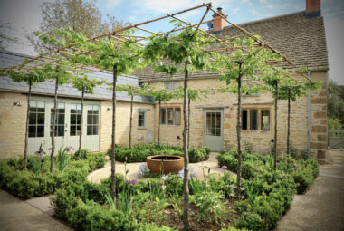 View of the entire parterre garden showing pleached trees, water feature and hoggin pathways.