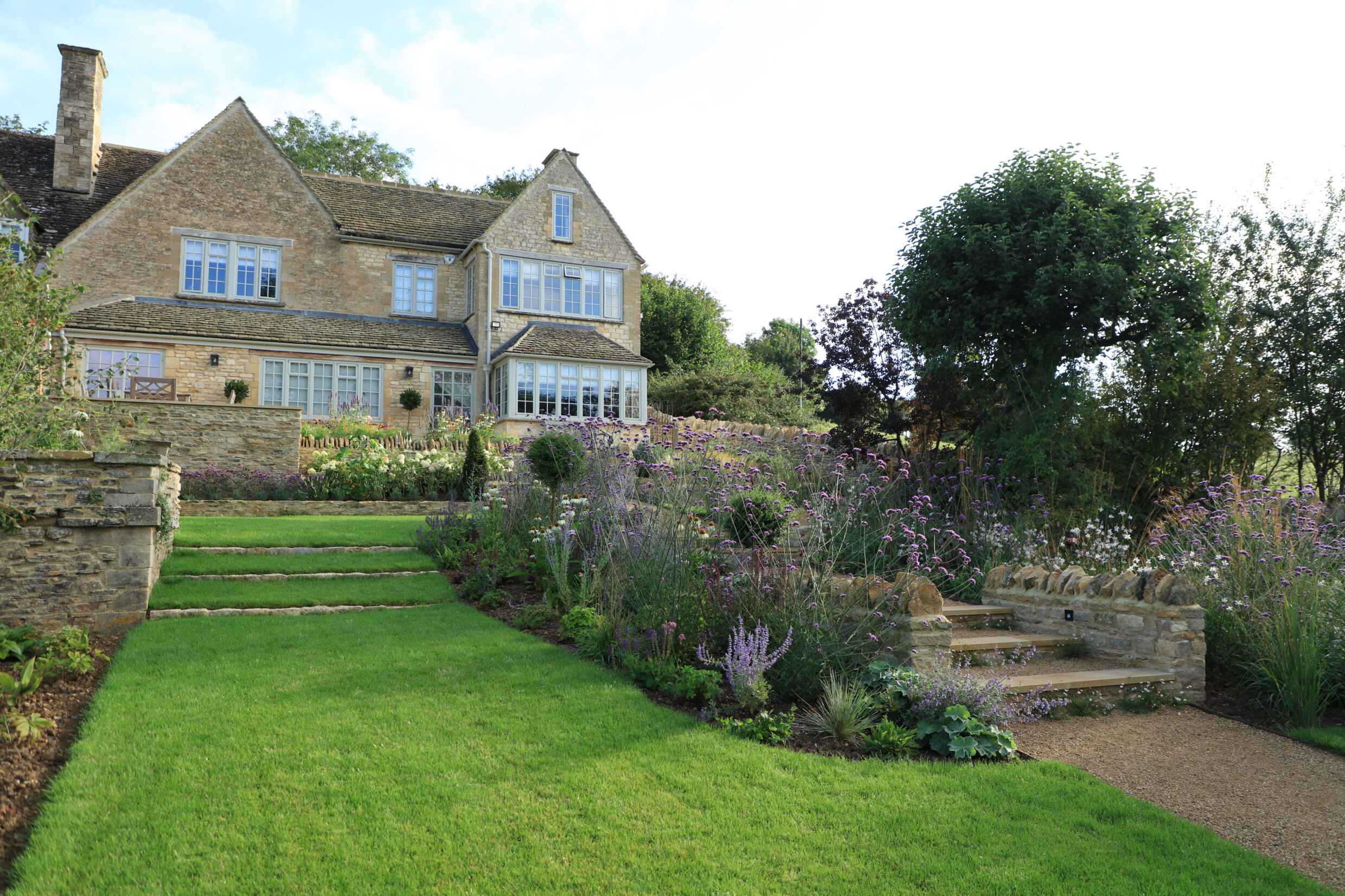 Fresh green grass lawn with meadow like borders and hoggin paths and steps