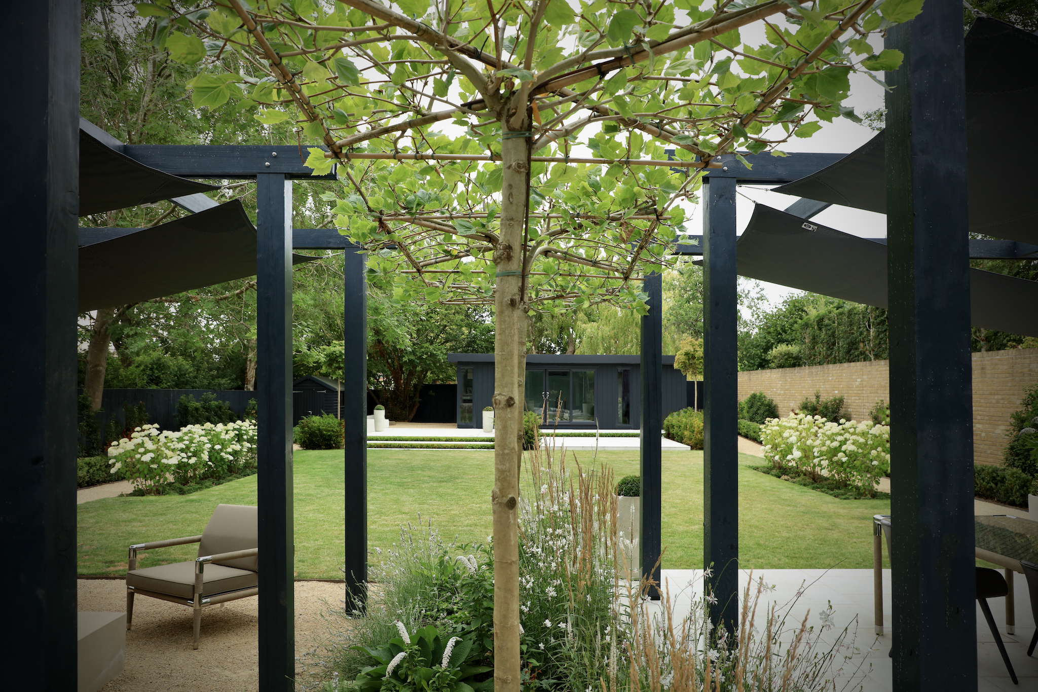 Symmetrical shot of roof pleached trees between arbor and sails