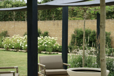 Pleached trees through the arbor looking on to realxed seating area with waterbowl and indian ocean furniture