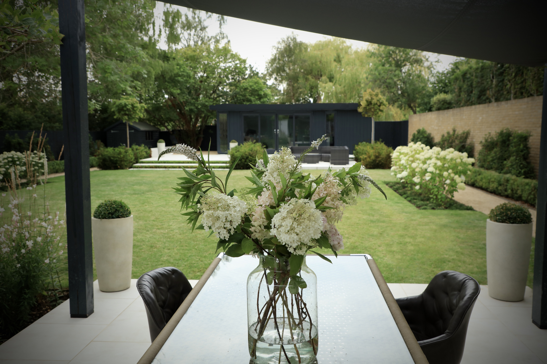 Freshly cut flowers in a vase on Indian Ocean dining table in Oxford townhouse garden