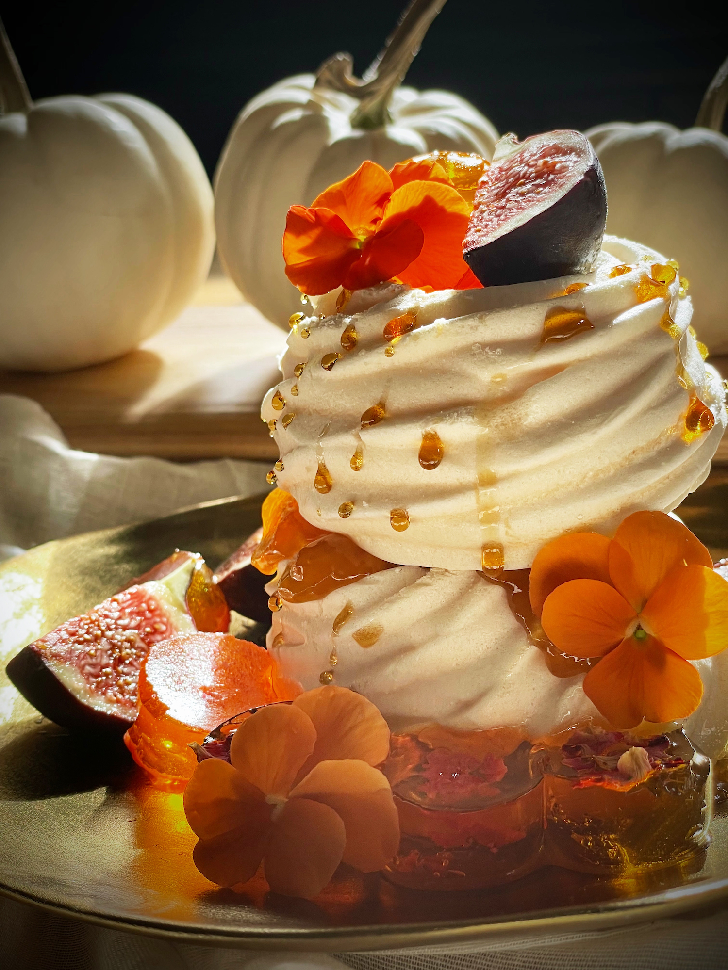 Meringue nests stuffed with honey and edible flowers. Garnished with seasonal figs