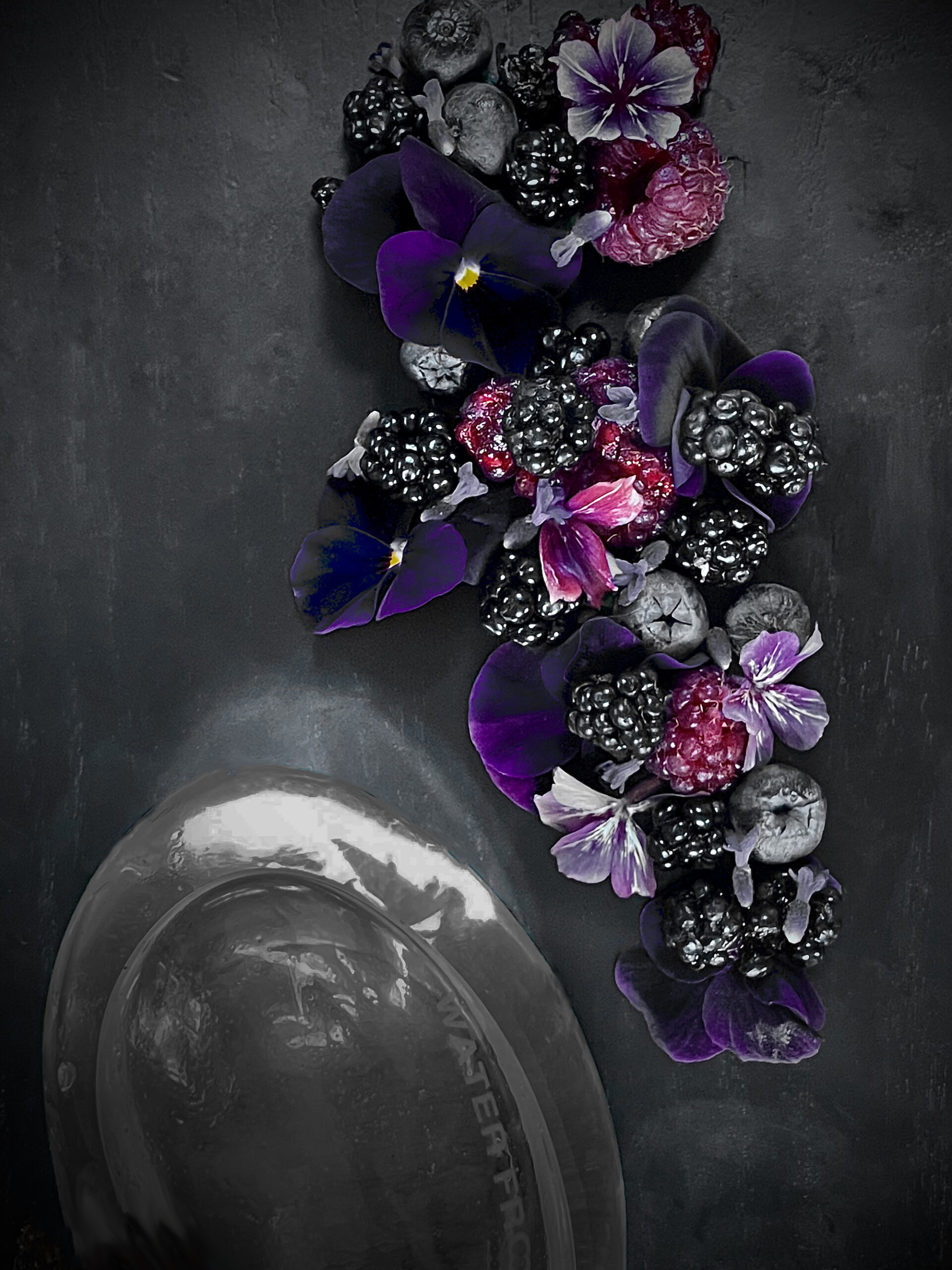 blackberry and blueberries on dark background with edible purple violas
