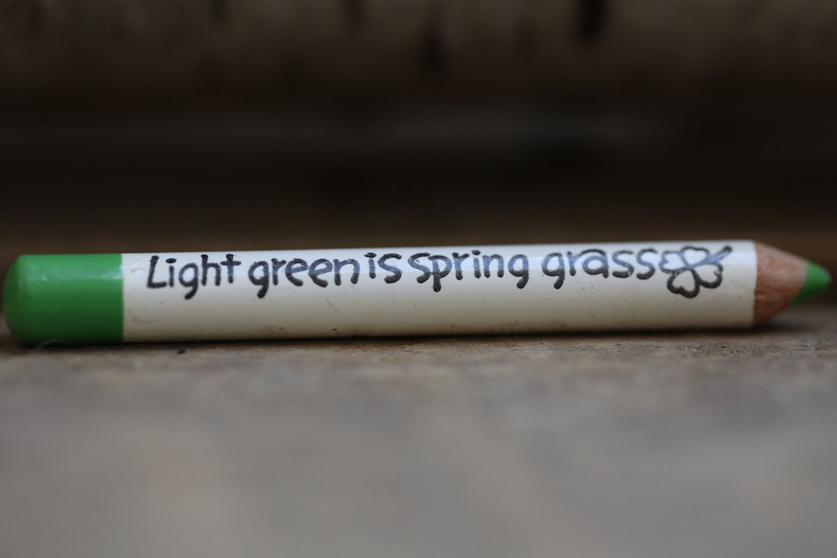 Light green is Spring grass. Green colouring pencil sitting on wooden counter top