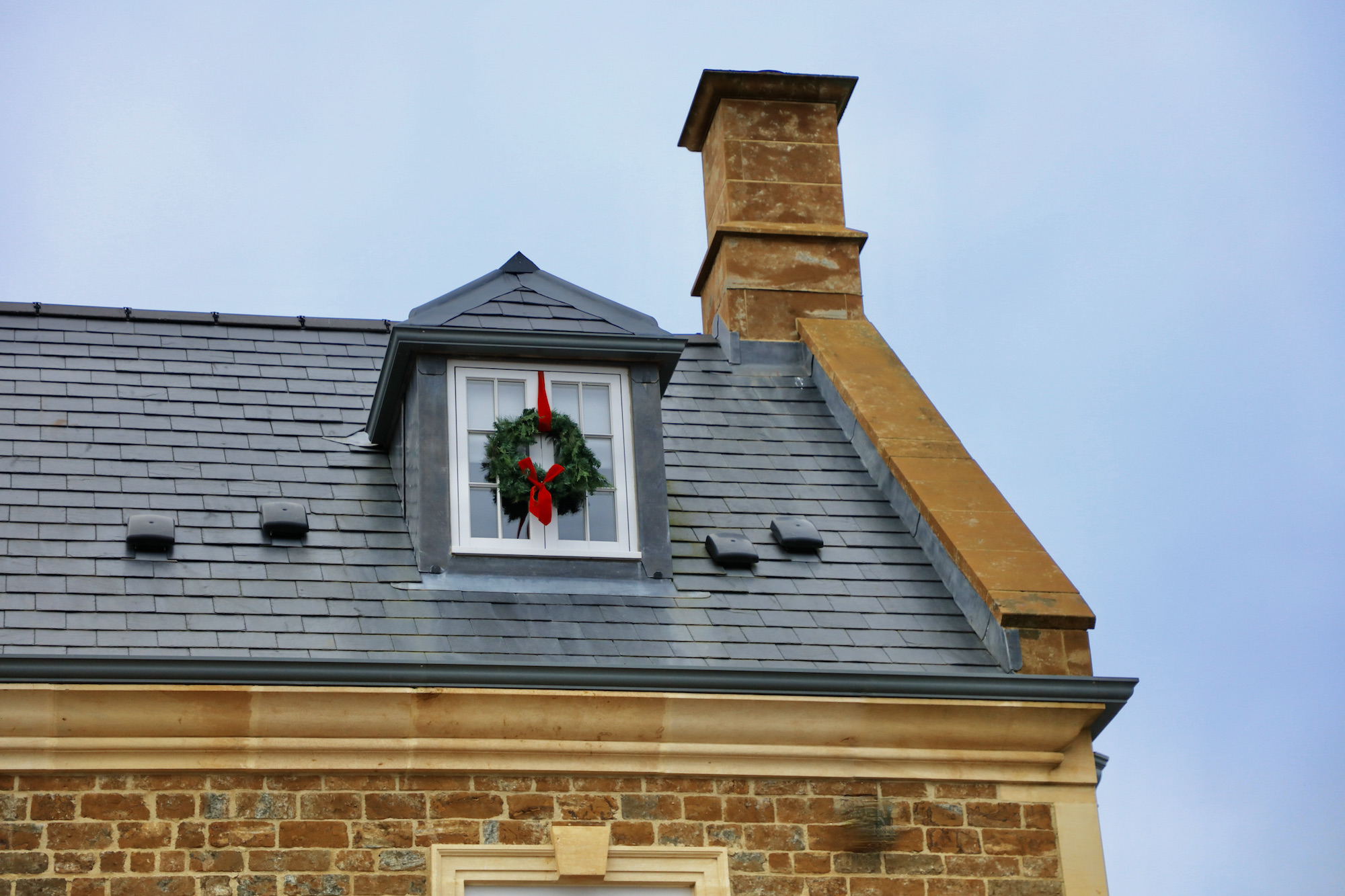 Rooftop window with conifer wreath and velvet red bows