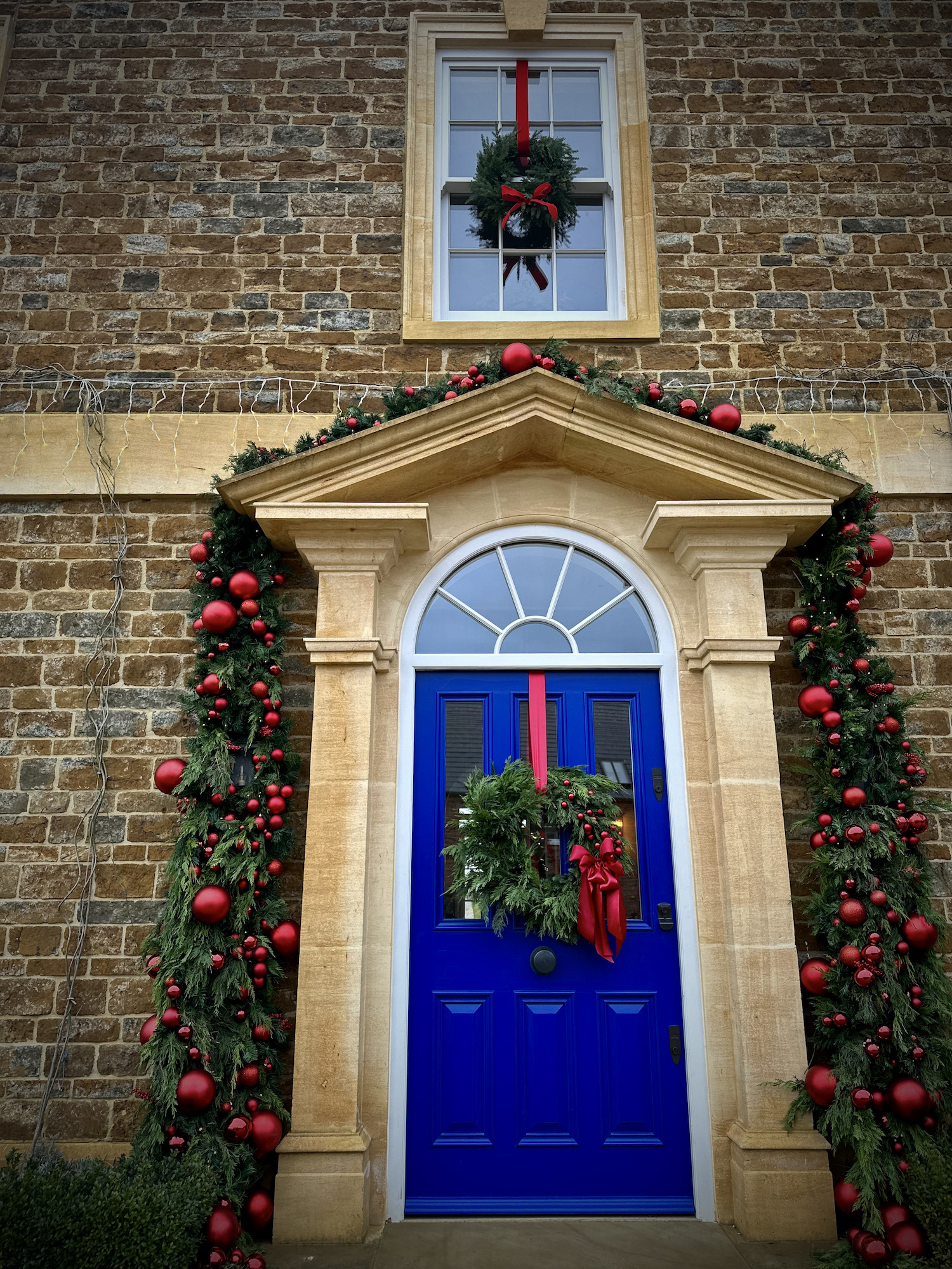 Christmas archway around pillared front door of Georgian manor house. Designed and installed by hendy curzon gardens 