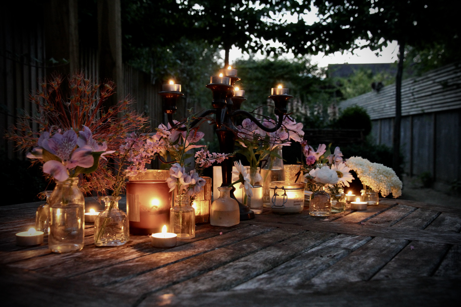 Hygge tablescape with warm peach candles and lanterns and fresh flowers