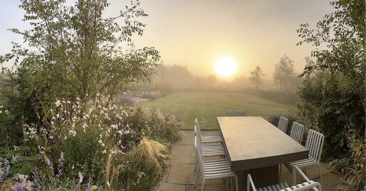 Modern country garden in Oxfordshire  cotswolds as featured in enki magazine. Sun rises over prairie planted garden with Hay Palisade furniture 